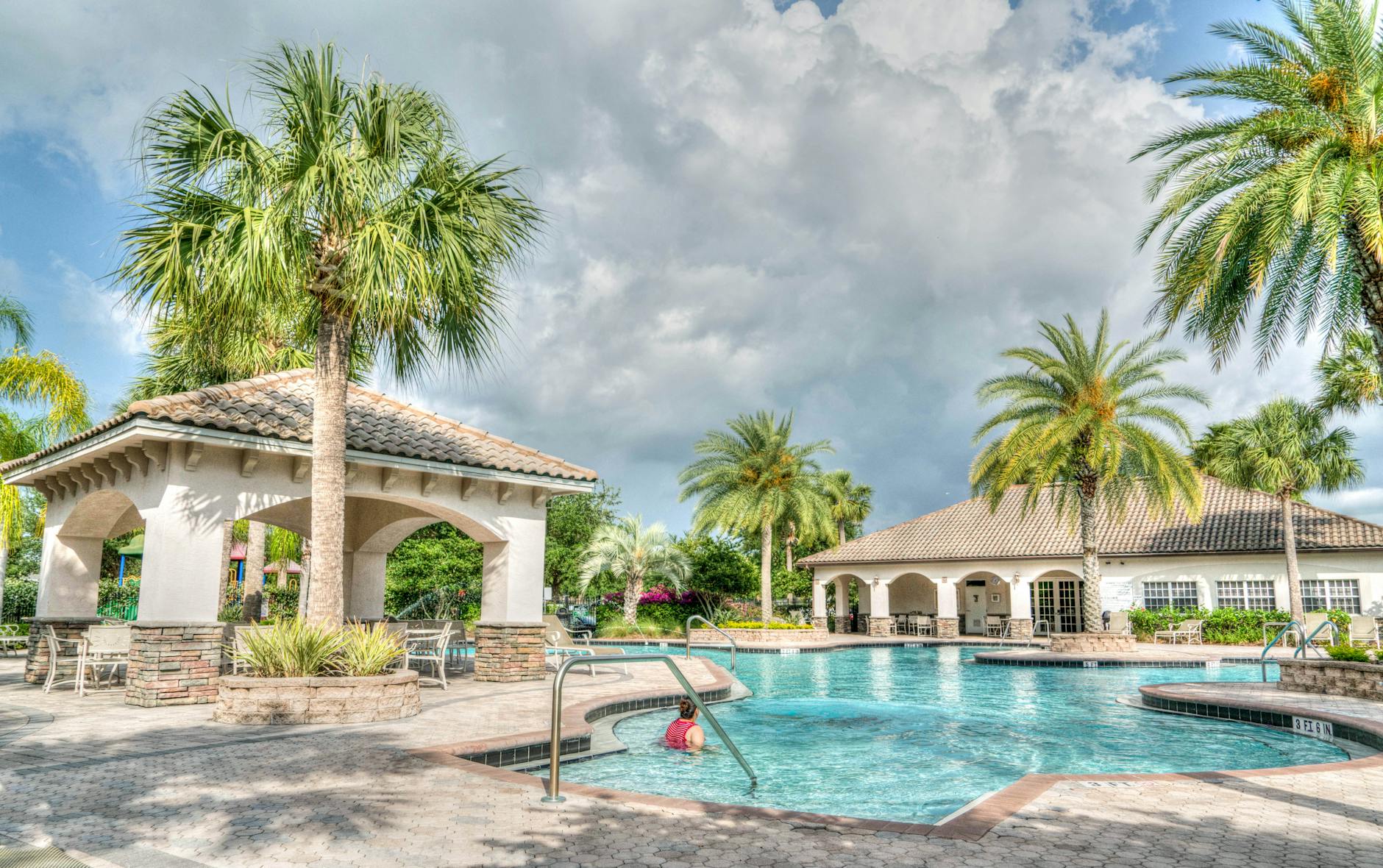 Beautiful tropical resort poolside scene featuring palm trees and crystal clear water